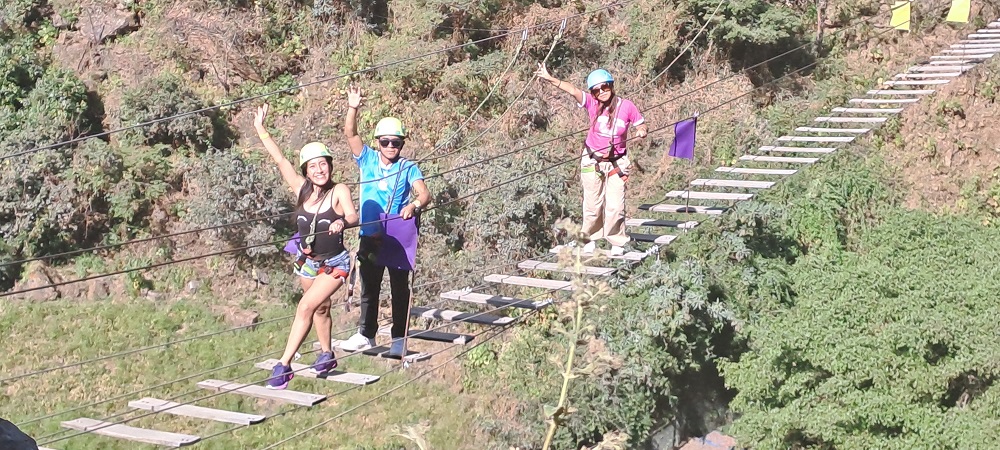 Tour de Aventura Cascas Extremo Grupo de viajeros cruzando un puente tibetano durante el Tour Cascas Extremo